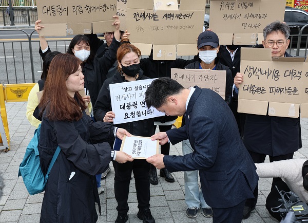 전세사기피해자전국대책위 및 시민사회대책위 회원들이 20일 서울 용산구 대통령집무실 인근에서 열린 전세사기 대책 관련 대통령 면담 요청 기자회견에서 시민사회수석실 행정관에게 면담요청서를 건네고 있다. [사진=연합뉴스]